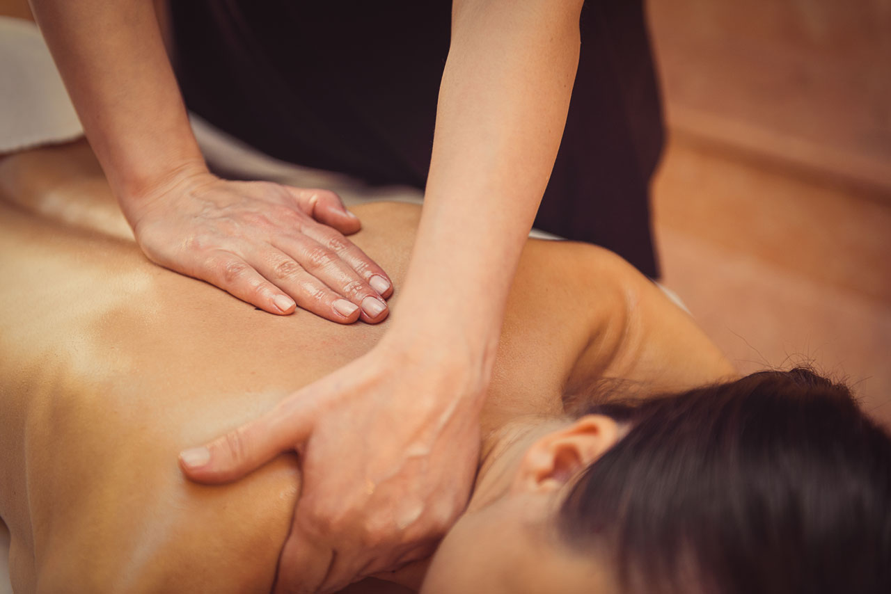 lady having her neck and upper back massaged while lying face down