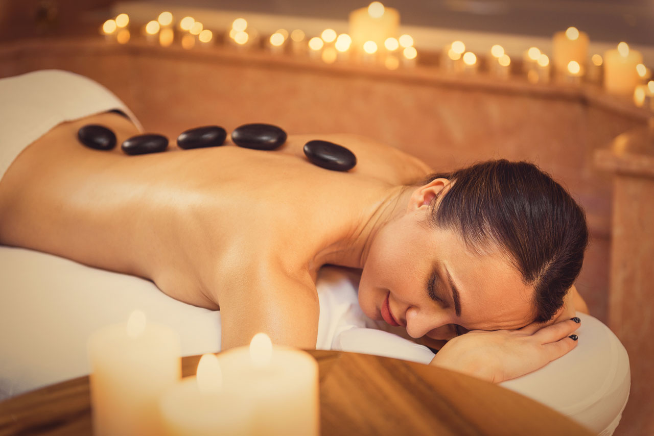 young lady lying face down relaxed with hot stones placed down her spine